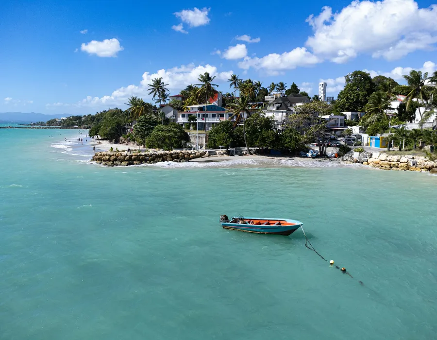 Small boat crossing calm, clear tropical water toward a private island