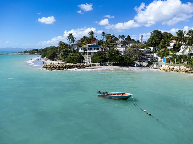 Small boat crossing calm, clear tropical water toward a private island