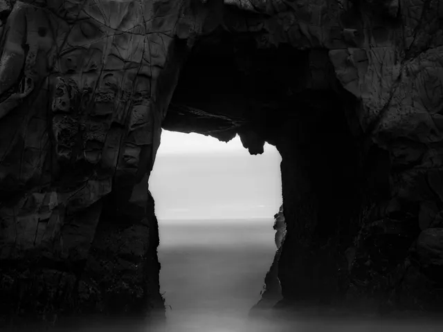 Sunlight streaming through the mouth of a coastal sea cave onto the ocean